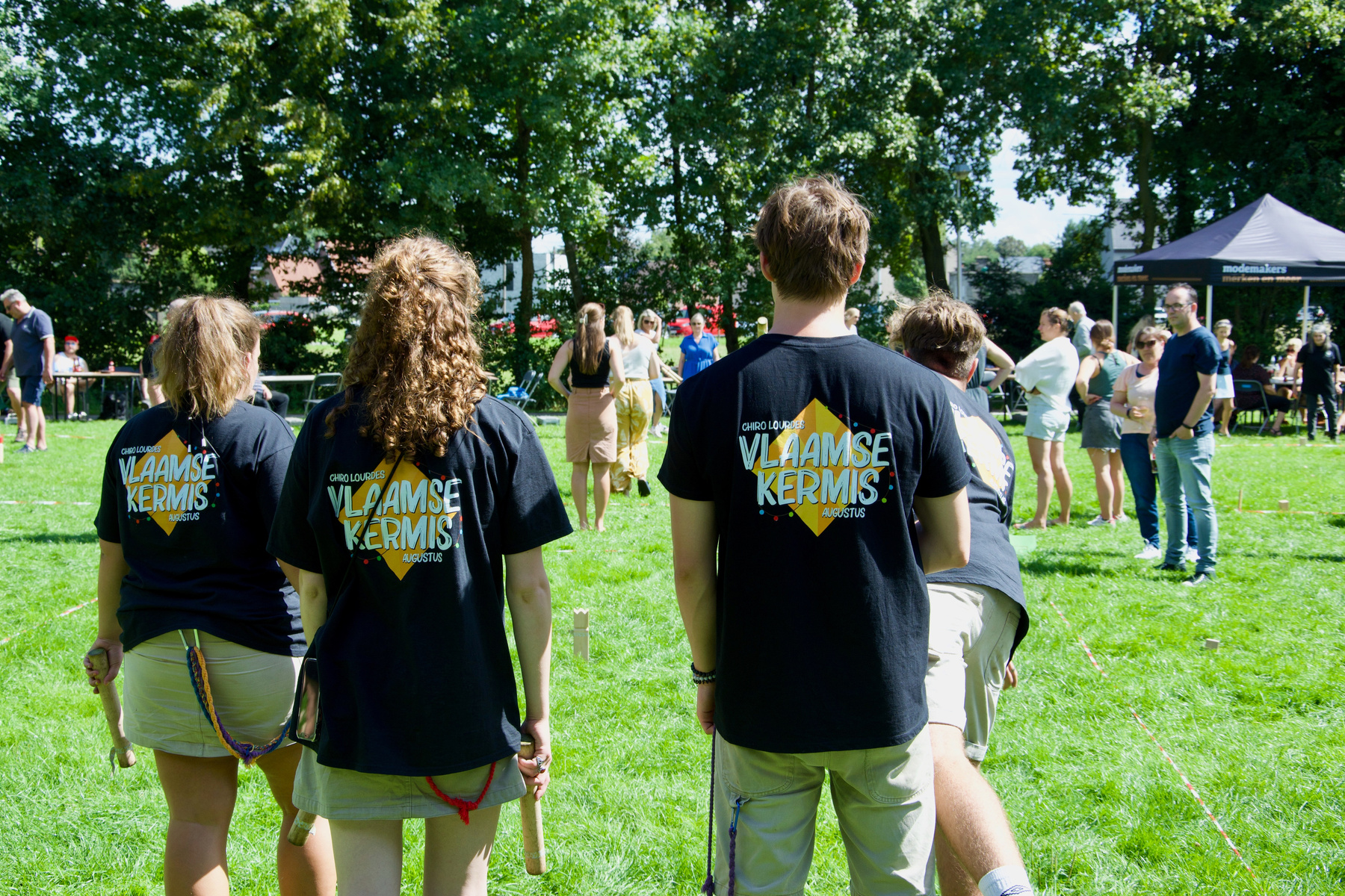 Persoon die kubb speelt, met logo Vlaamse kermis op t-shirt